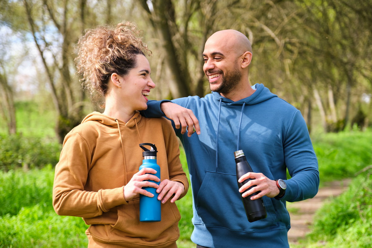 a man and a woman are smiling and holding water bottles.